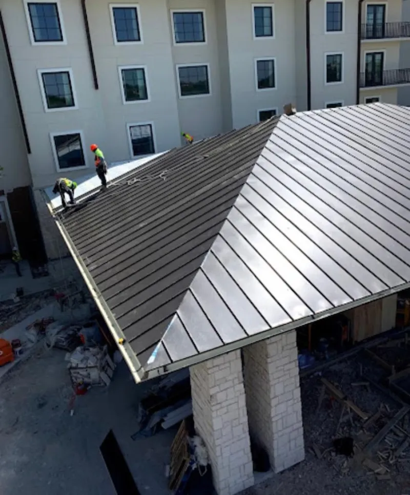 Crew installing standing seam metal roof panels on a commercial project in Sault Ste. Marie